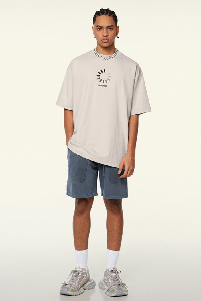 Man in cream loading tee standing with casual posture.