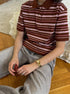 Close-up of brown striped polo shirt with cream and pink lines, styled with gold watch.
