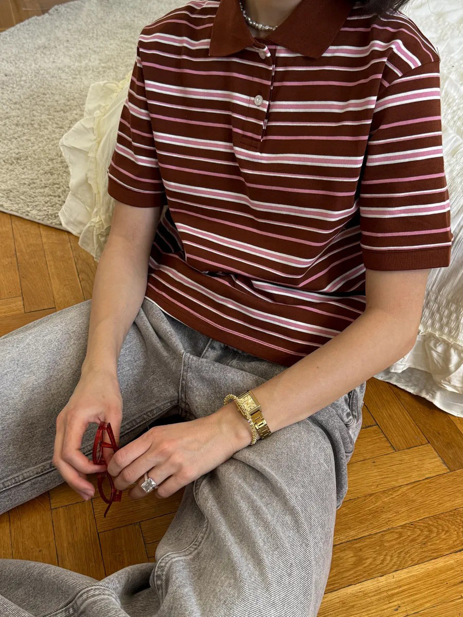 Close-up of brown striped polo shirt with cream and pink lines, styled with gold watch.