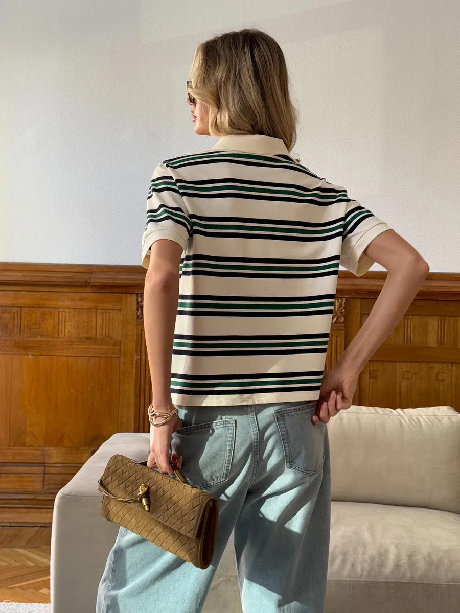 Back view of model in striped polo shirt and loose light-wash jeans, holding tan clutch.