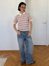 Full-body view of model in retro striped polo shirt and oversized wide-leg jeans.
