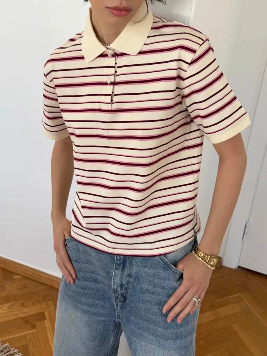 Model wears striped polo shirt with short sleeves and spread collar, hands in jeans pockets.