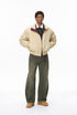 Model in beige men bomber jacket with green pants, relaxed pose