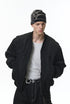 Black bomber with cap, hands in pockets, minimalist front look
