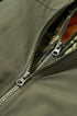 Zipper close-up on olive bomber jacket with orange lining peek