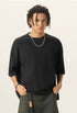 Medium shot of model styling a black 100% cotton french terry boxy short sleeve tee with a silver chain.