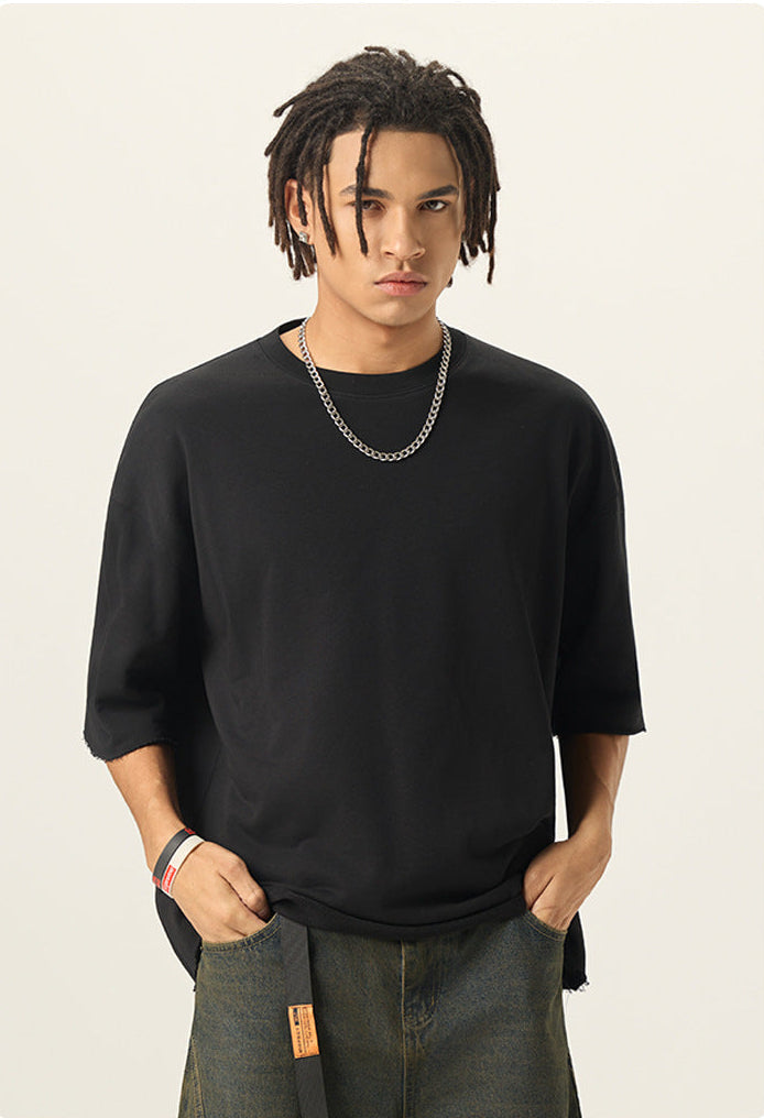 Medium shot of model styling a black 100% cotton french terry boxy short sleeve tee with a silver chain.