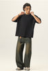 Full length view of model wearing a black heavyweight boxy fit t shirt with raw edges and wide leg jeans.