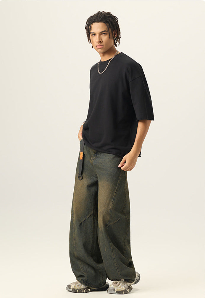 Three quarter side view of model wearing a black heavy cotton boxy t shirt with raw edge sleeves.