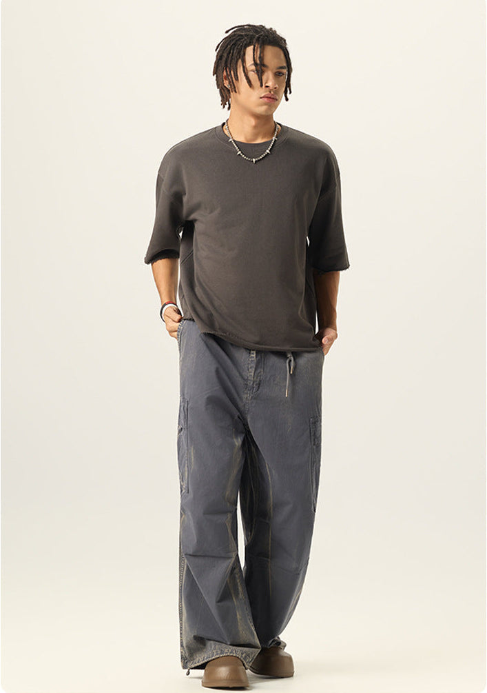 Full length shot of model styled in a charcoal grey boxy fit crewneck tee and loose cargo pants.