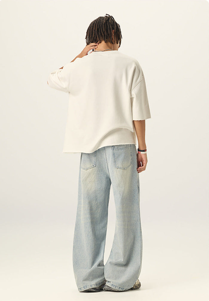 Back view of model wearing an off white heavyweight boxy t shirt showing loose fit and raw bottom hem.