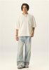Full length view of model wearing an off white boxy cropped t shirt with light wash baggy jeans.