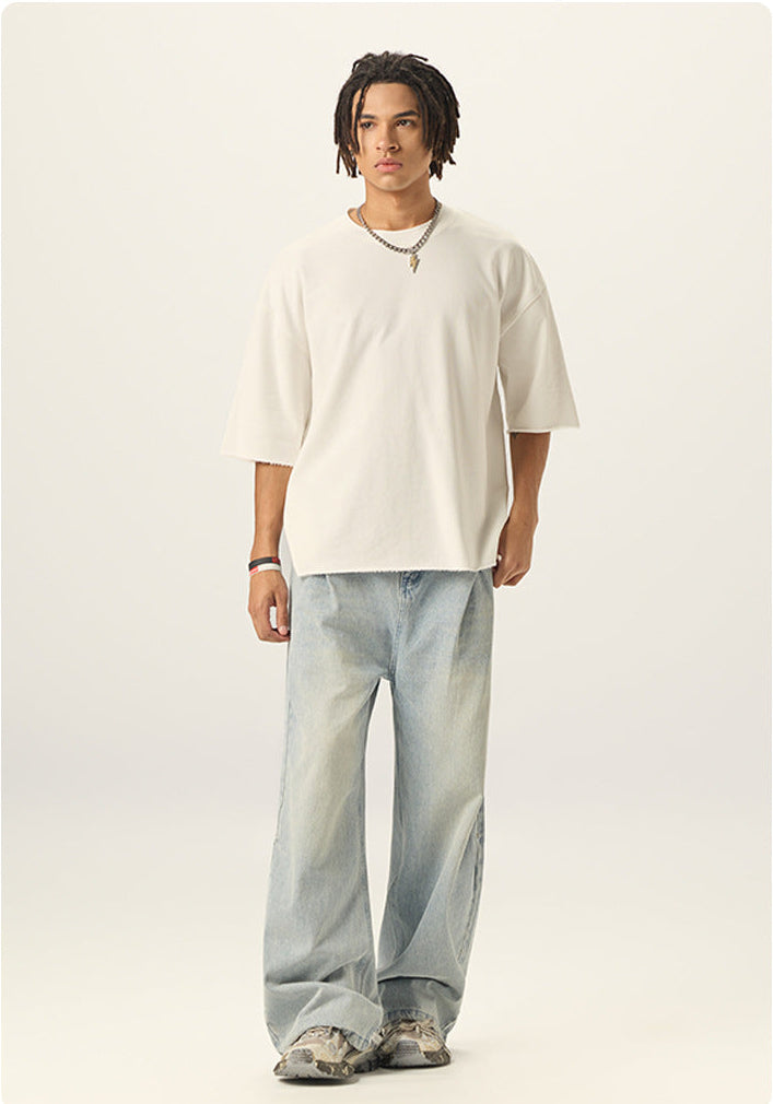 Full length view of model wearing an off white boxy cropped t shirt with light wash baggy jeans.