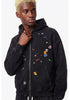 Upper body shot of model wearing a washed black cotton blend full zip hoodie with colorful patch embroidery.