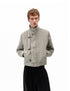 Upper body view of model wearing a khaki beige canvas jacket featuring metal clasp front closures and high collar.