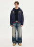 Full length view of model wearing a navy blue boxy cropped zip up hoodie with vintage wash jeans and tan boots.