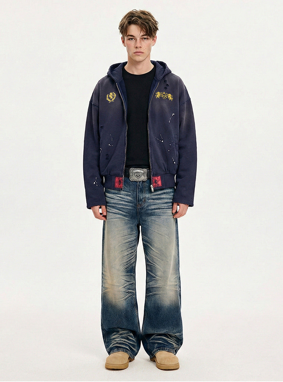Full length view of model wearing a navy blue boxy cropped zip up hoodie with vintage wash jeans and tan boots.