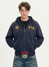 Medium shot of model wearing a navy blue 100% cotton zip up hoodie with chest crest embroidery and distressed details.