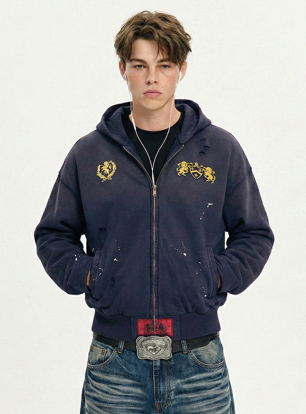 Medium shot of model wearing a navy blue 100% cotton zip up hoodie with chest crest embroidery and distressed details.
