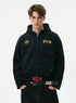 Model wearing a washed black distressed zip up hoodie with paint splatter and gold chest crest embroidery.
