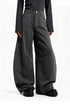 Low angle close up of model wearing charcoal gray wide leg cargo trousers showing curved seam panels and platform shoes.