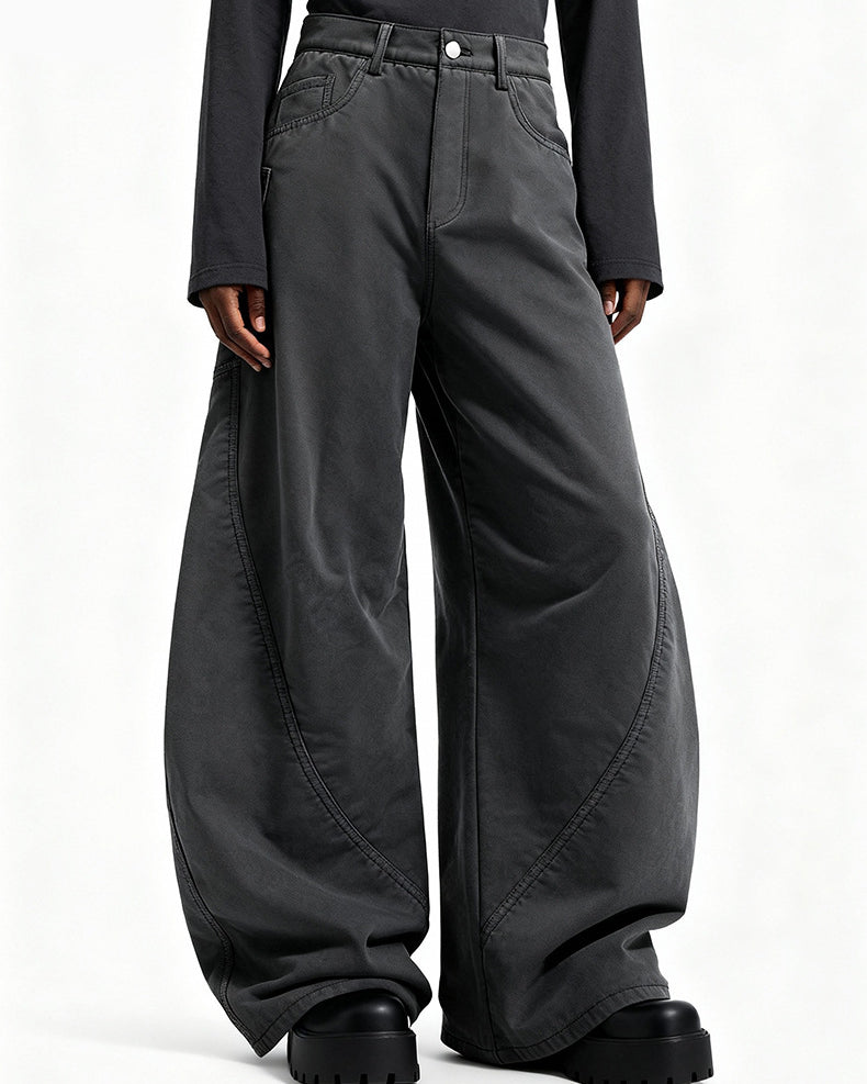 Low angle close up of model wearing charcoal gray wide leg cargo trousers showing curved seam panels and platform shoes.