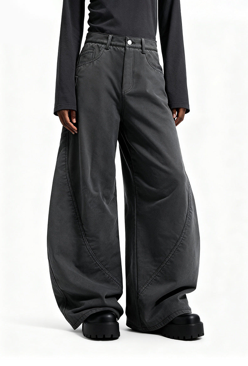 Low angle close up of model wearing charcoal gray wide leg cargo trousers showing curved seam panels and platform shoes.