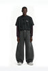 Front view of model wearing charcoal gray wide leg curved cargo pants paired with distressed long sleeve shirt.