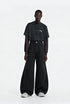 Full length shot of model styling washed black fleece lined wide leg curved seam cargo pants with a long sleeve tee.