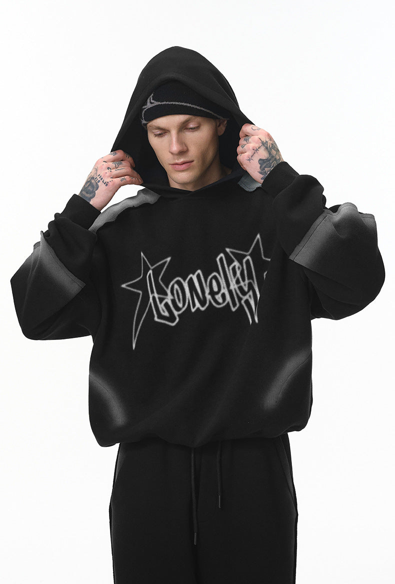 Male model adjusting hood, black graphic hoodie, relaxed front view.