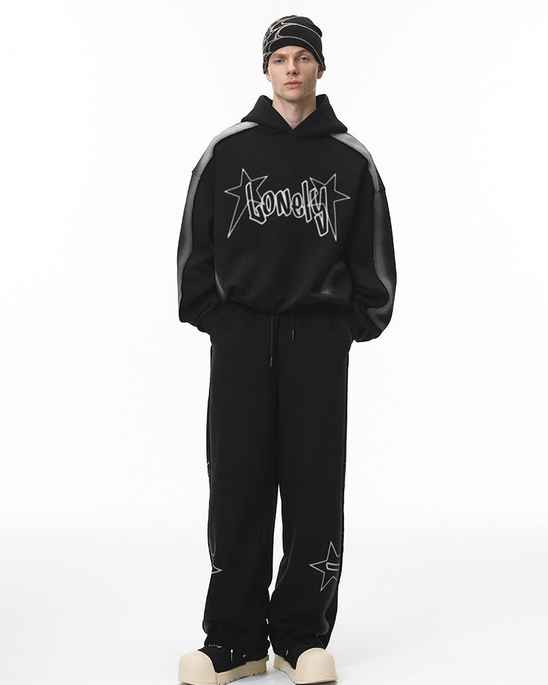 Full body male model in black graphic hoodie and matching sweatpants, front.