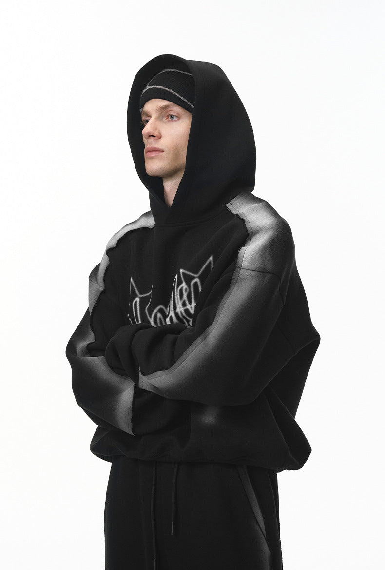 Side view of black graphic hoodie on model showing drop shoulder.