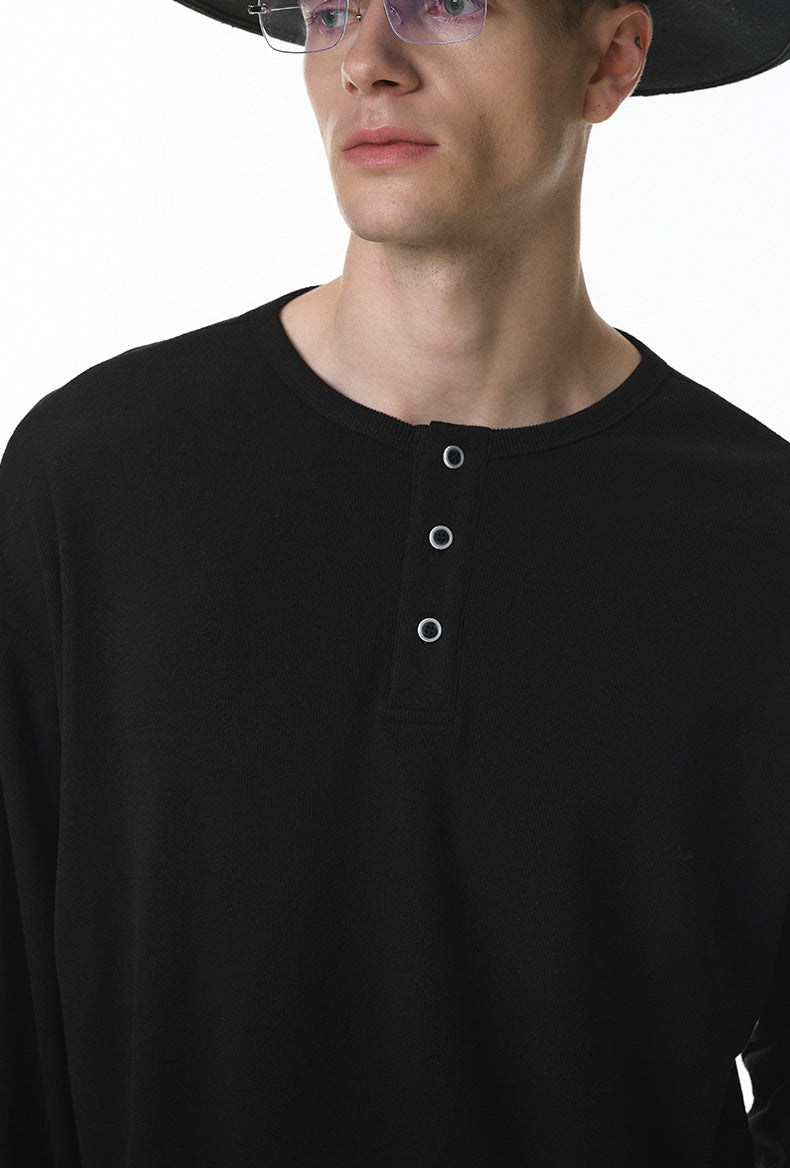 Man wearing a black long sleeve henley t shirt and dark sunglasses on a white background