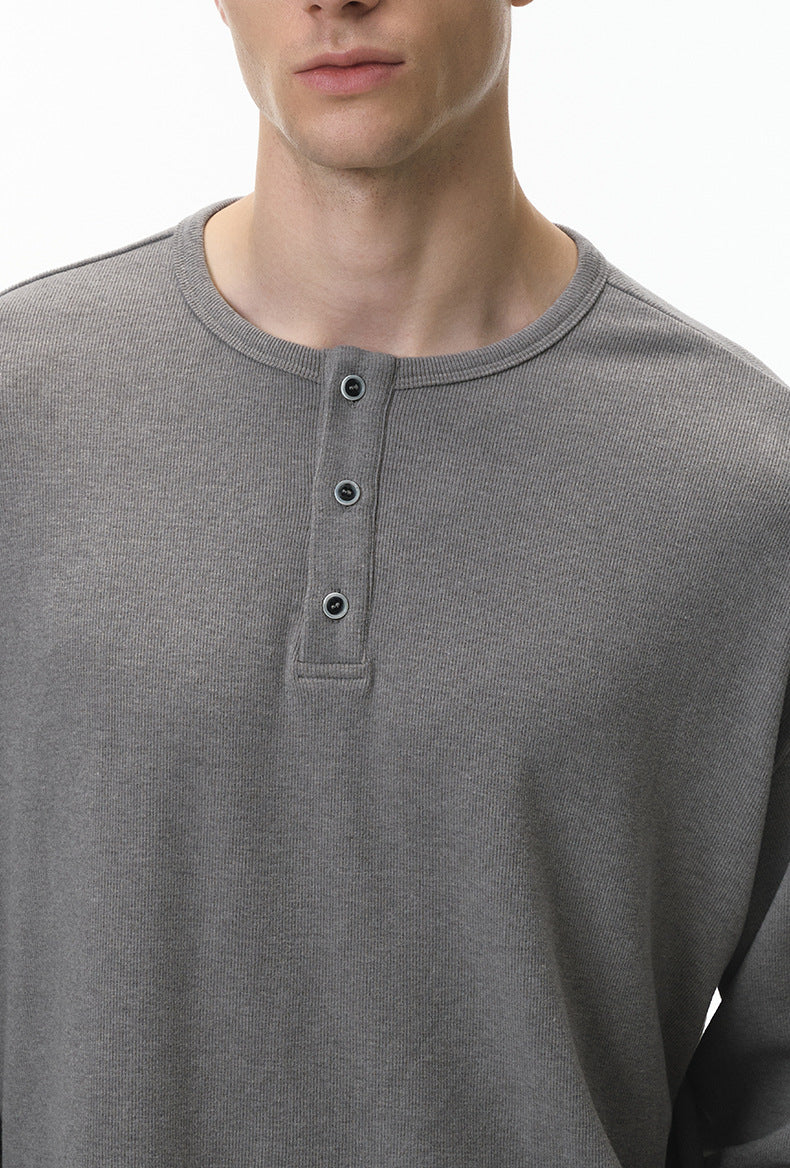 Close-up of a gray long-sleeve henley shirt worn by a person.