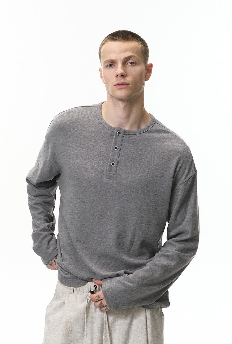 Man wearing a gray long-sleeve henley shirt on a white background