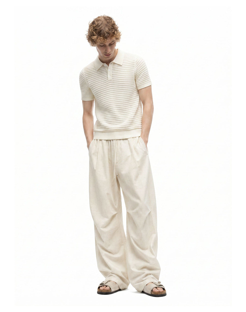 Men's ivory wide-leg drawstring pants styled with an open-knit polo and sandals.