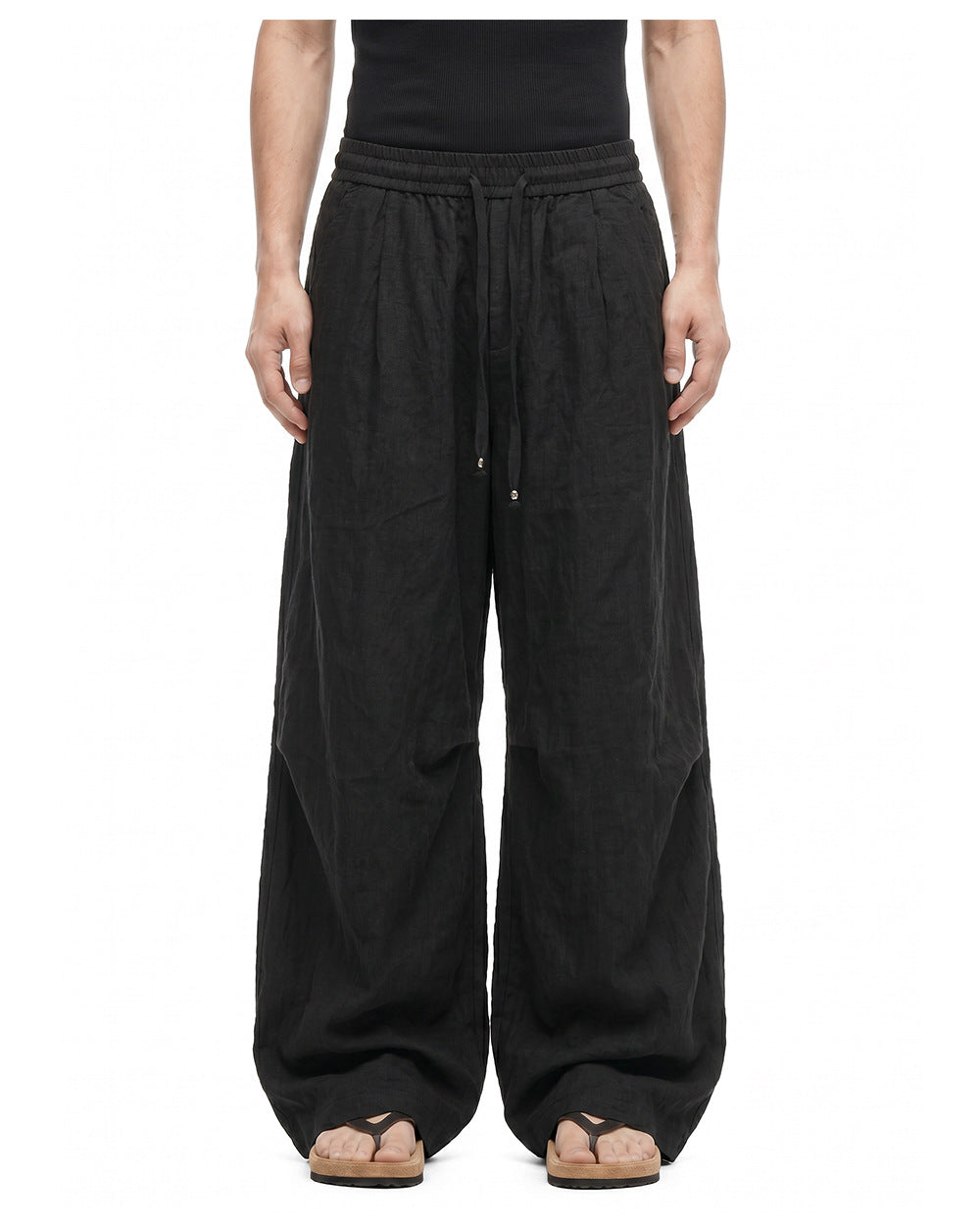 Men's black wide-leg pants showing elastic drawstring waist and curved leg shaping.