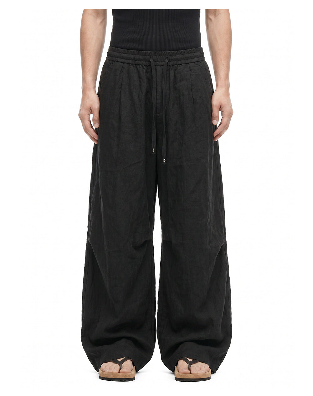 Men's black wide-leg pants showing elastic drawstring waist and curved leg shaping.