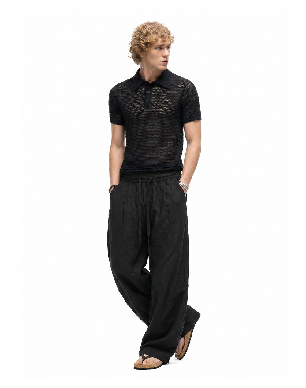 Black relaxed drawstring pants styled with a black knit polo and sandals.