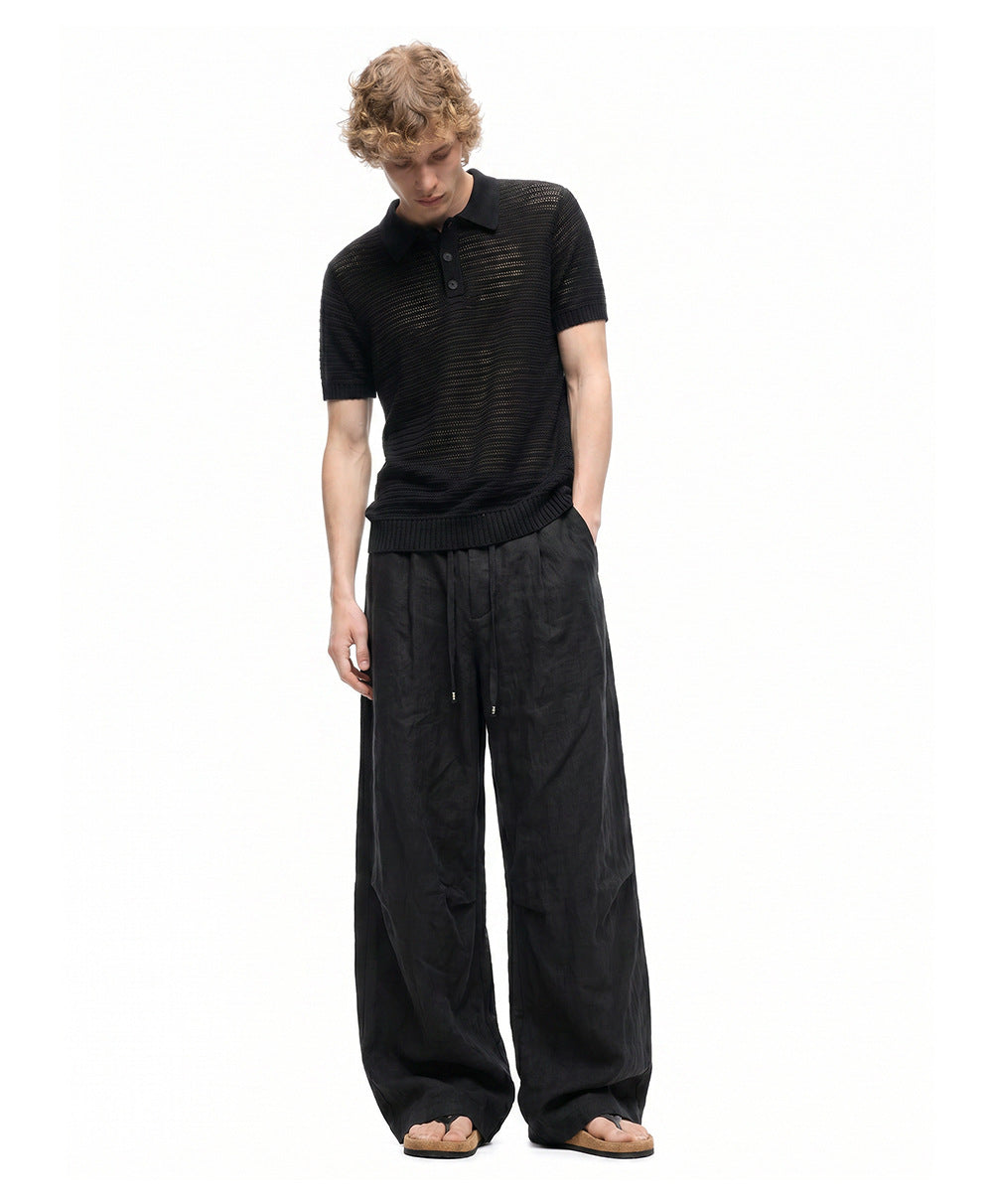 Full-length front view of men's black wide-leg pants with side pockets.