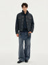 Full-length front view of dark indigo jacket worn open over a dark shirt and wide-leg jeans