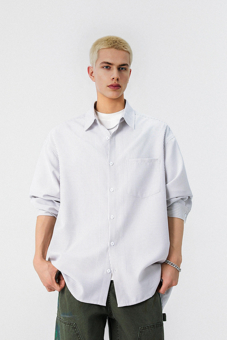 Front shot of model wearing a grey and white pinstripe long sleeve button up shirt with dark pants.