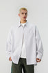 Medium shot of model wearing an unbuttoned grey vertical striped long sleeve shirt over white tee.