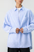 Mid-section shot of a light blue vertical pinstripe long sleeve button down shirt on model.