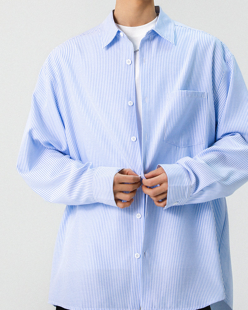 Mid-section shot of a light blue vertical pinstripe long sleeve button down shirt on model.