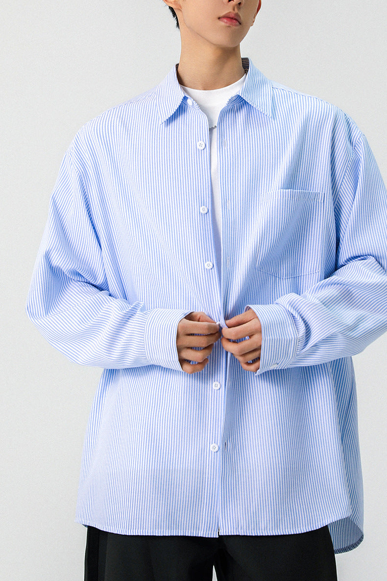 Mid-section shot of a light blue vertical pinstripe long sleeve button down shirt on model.