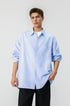 Half length front shot of model wearing a light blue long sleeve pinstripe shirt with rolled cuffs.