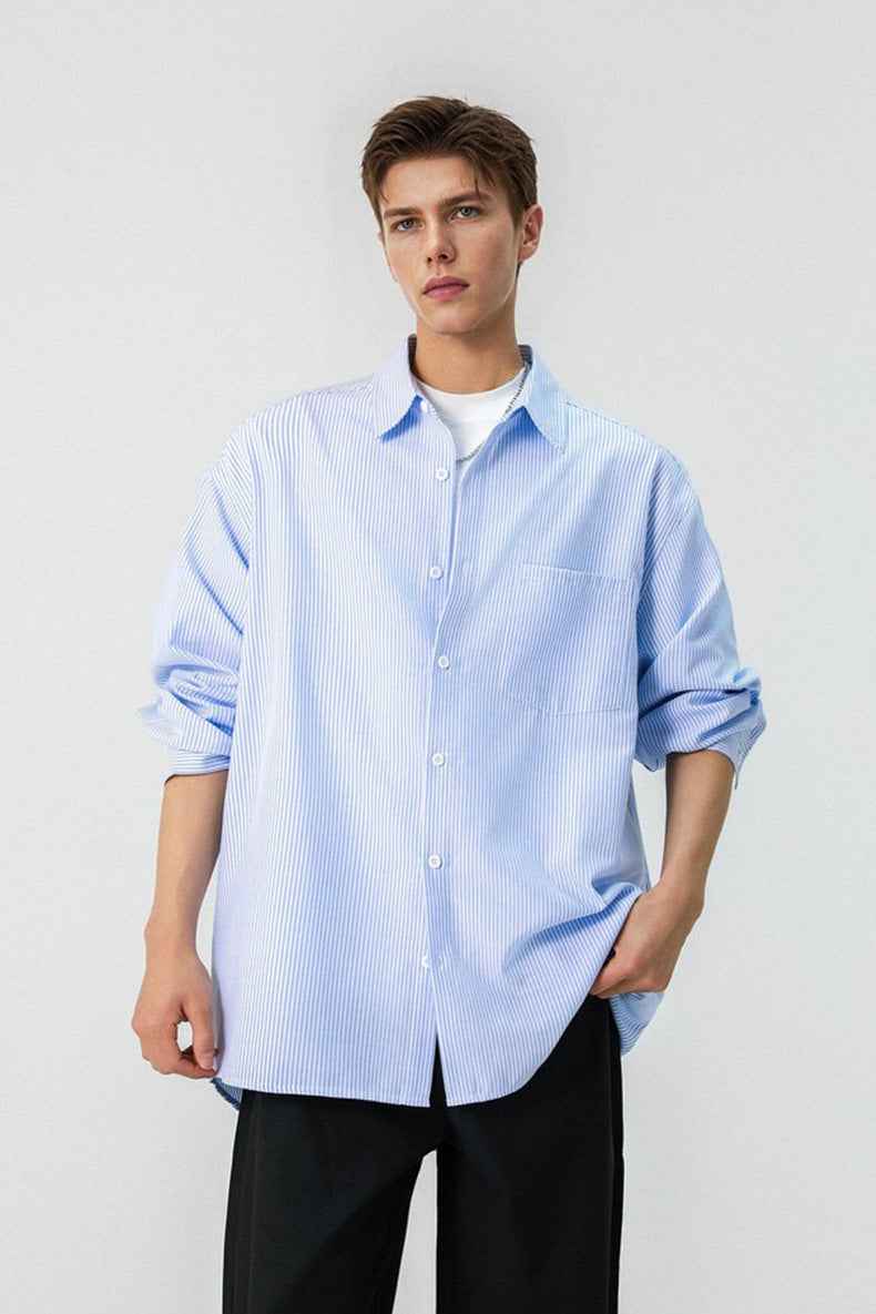 Half length front shot of model wearing a light blue long sleeve pinstripe shirt with rolled cuffs.