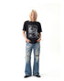 Men's vintage-style punk graphic T-shirt in black styled with distressed wide-leg jeans.