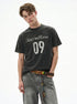 Washed black boxy graphic tee with distressed 09 print and gray denim.